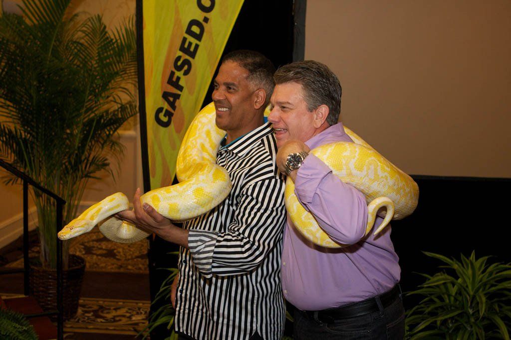 Two men are holding a large snake on their shoulders.