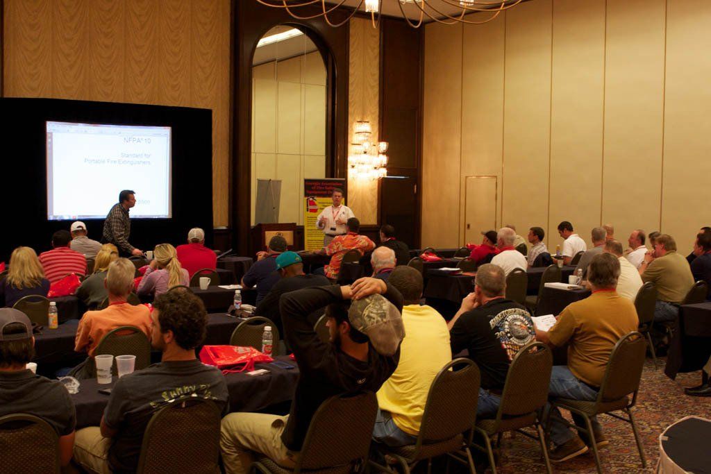 A group of people are sitting at tables in a conference room