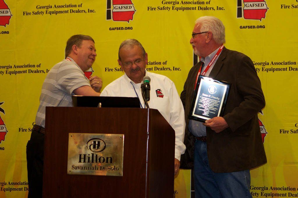 Three men standing in front of a podium that says hilton