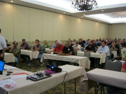 A group of people are sitting at tables in a conference room