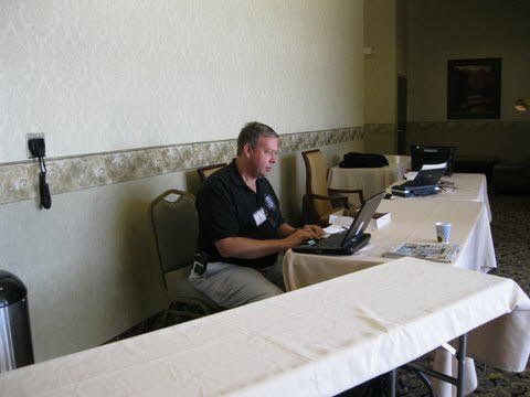 A man is sitting at a table with a laptop on it.