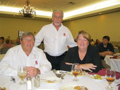 Three people are sitting at a table with plates of food and wine glasses.