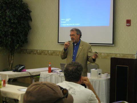 A man is giving a presentation in front of a projector screen.