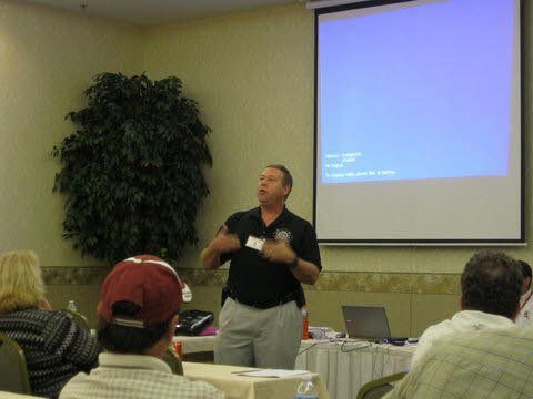 A man is giving a presentation to a group of people in front of a projector screen.