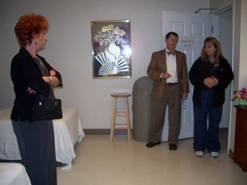 A man in a suit and bow tie is standing next to two women in a room.