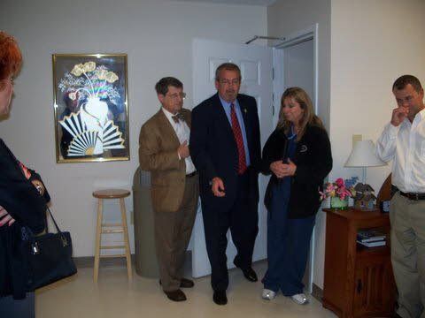 A group of people are standing in a room with a picture on the wall.