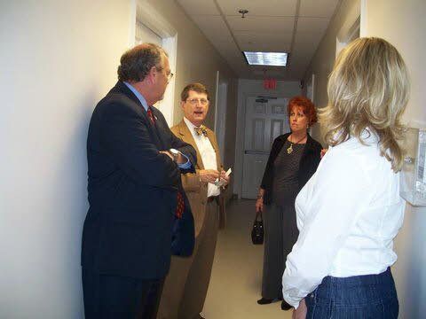 A group of people are standing in a hallway talking to each other.
