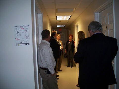 A group of people are standing in a hallway talking to each other.