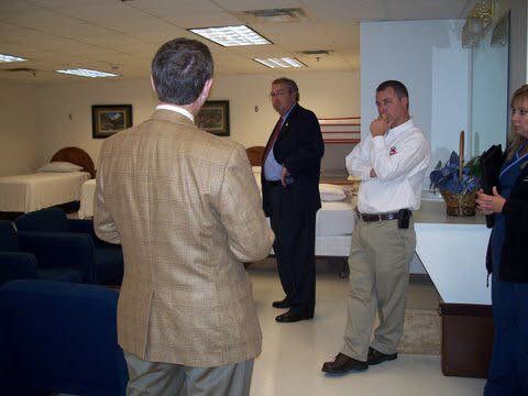 A group of men are standing in a room talking to each other.