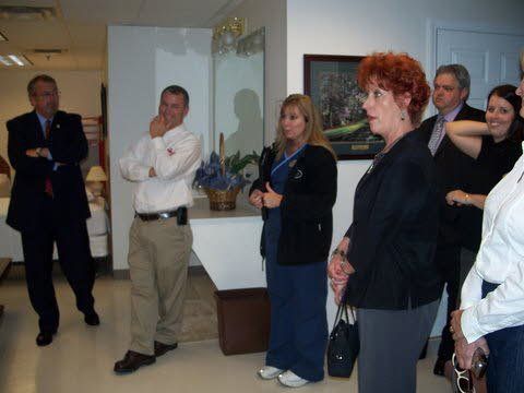 A group of people are standing in a room with a picture on the wall