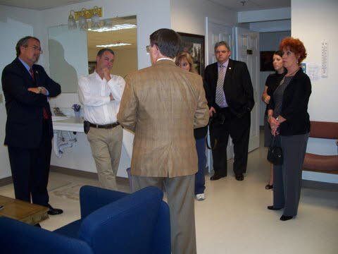 A group of people are standing in a room talking to each other.