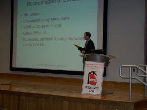 A man is giving a presentation at a podium in front of a large screen.