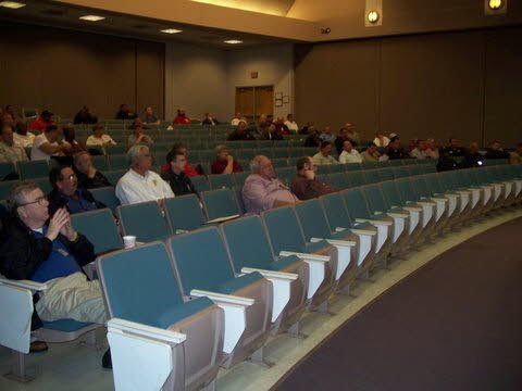 A group of people are sitting in rows of chairs in an auditorium.