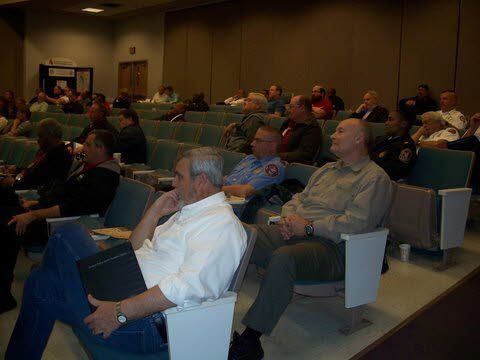A group of people are sitting in a lecture hall watching a presentation.