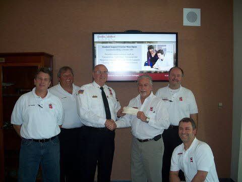 A group of men are posing for a picture in front of a television.