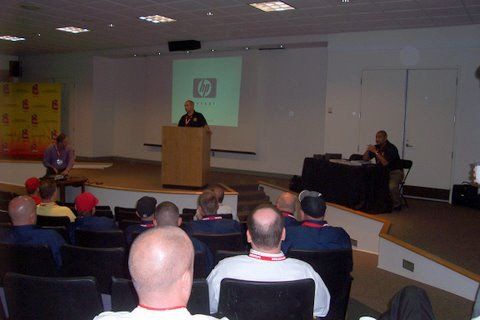 A group of people are sitting in front of a hp projector screen