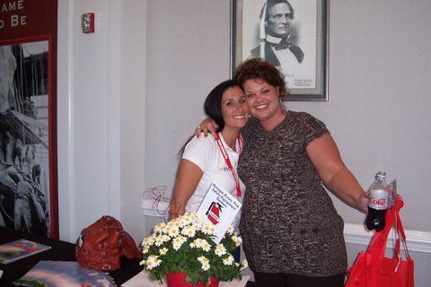 Two women are posing for a picture in front of a picture of abraham lincoln