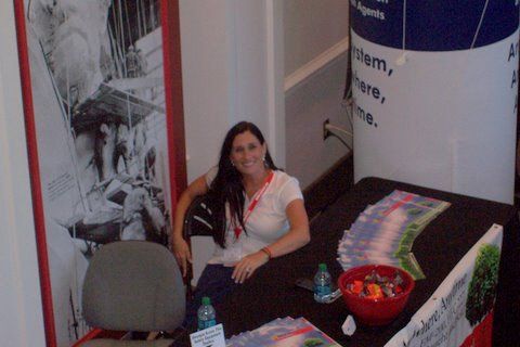 A woman is sitting at a table in front of a sign that says