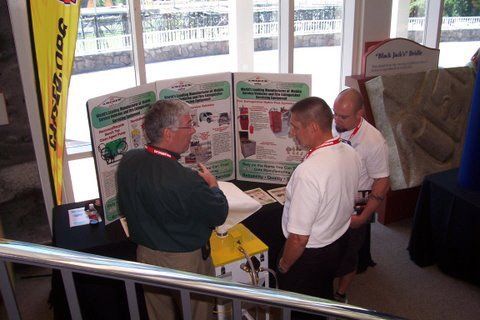 A group of men are standing around a table with a dunlop banner in the background