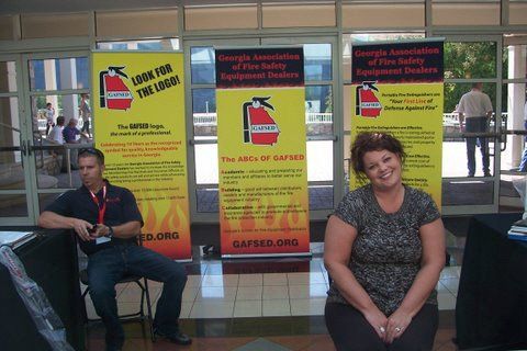 A man and a woman sit in front of a sign that says look for the logo