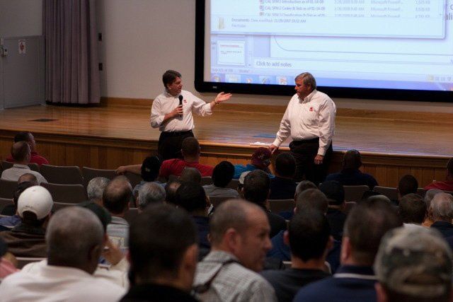 Two men are giving a presentation in front of a large screen