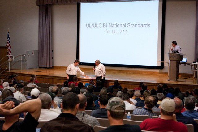 A group of people are sitting in front of a screen that says u.s. ulc national standards for ul-711