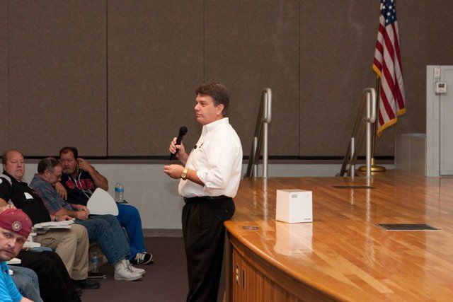 A man speaking into a microphone in front of a crowd
