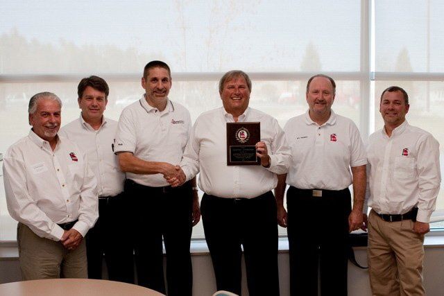 A group of men standing next to each other holding a plaque