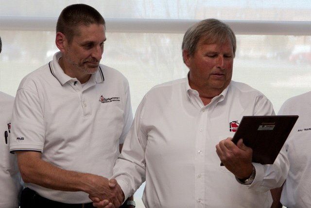 A man in a white shirt is shaking hands with another man