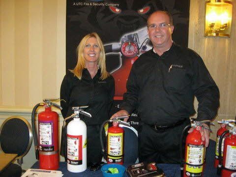 A man and a woman standing next to fire extinguishers