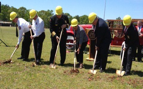 A group of people wearing hard hats are digging in a field