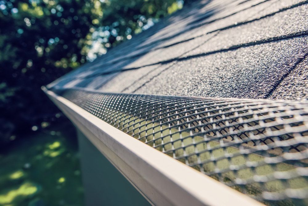 A close up of a gutter with a mesh covering on a roof.