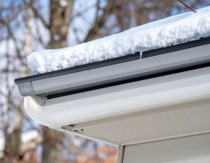 White house gutter with snow and icicles.