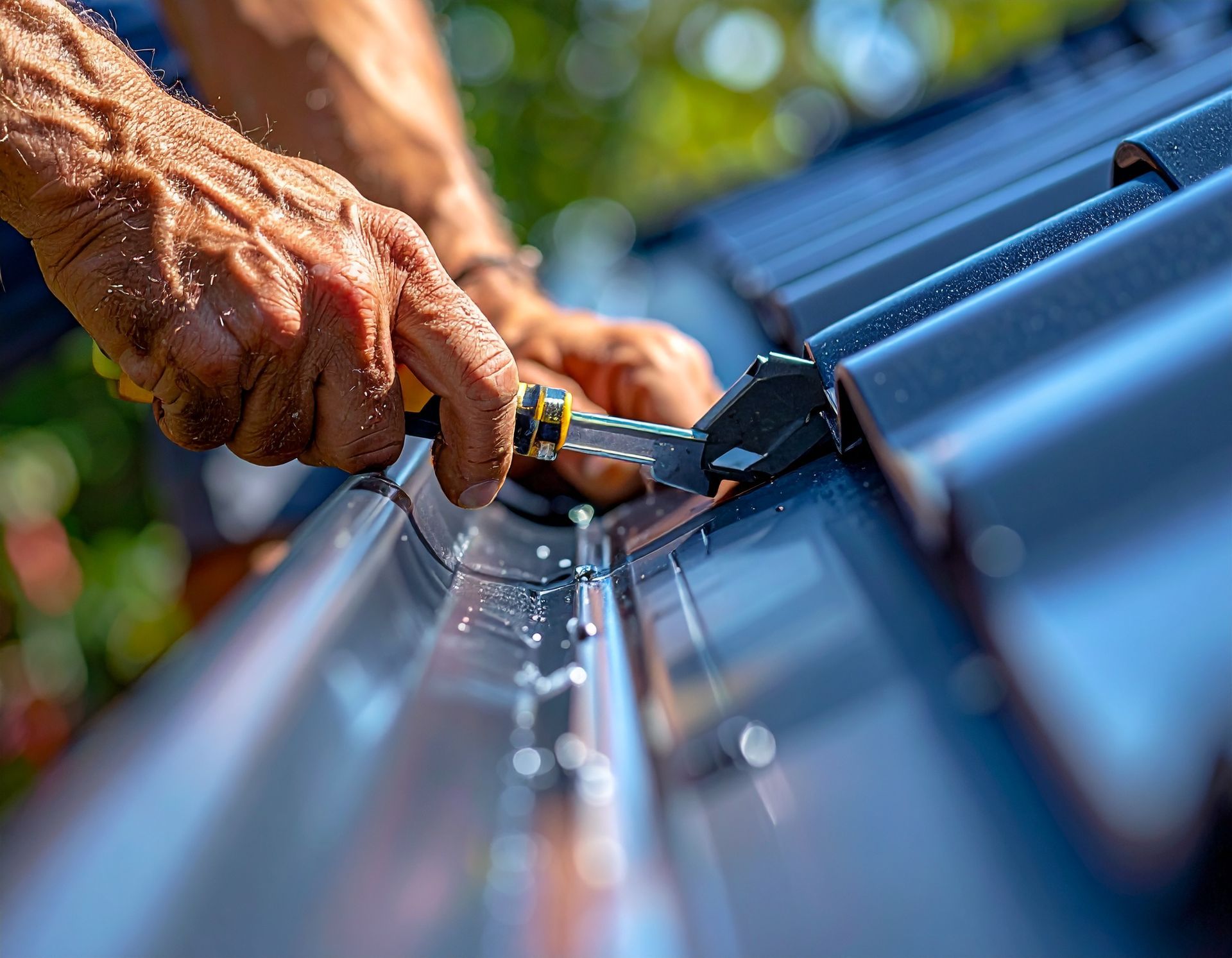 Hands using a tool to secure a metal roof panel during installation