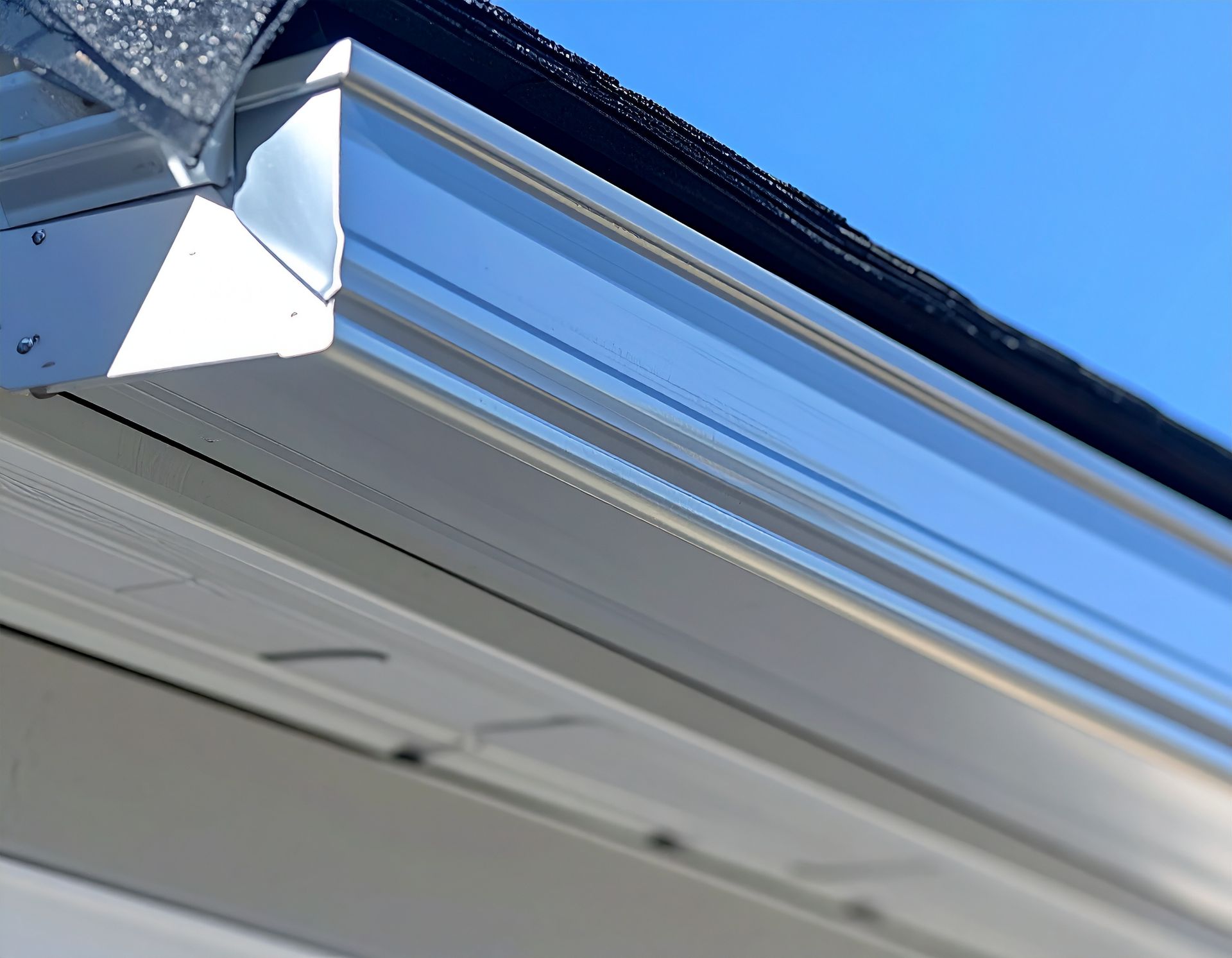 Close-up of a white gutter and roof eave against a blue sky