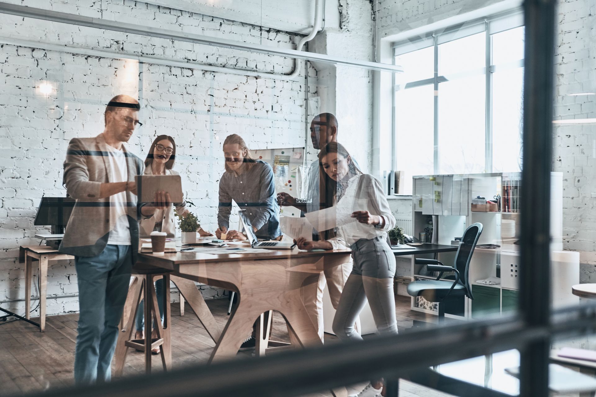 a group of people standing around a table looking at a tablet