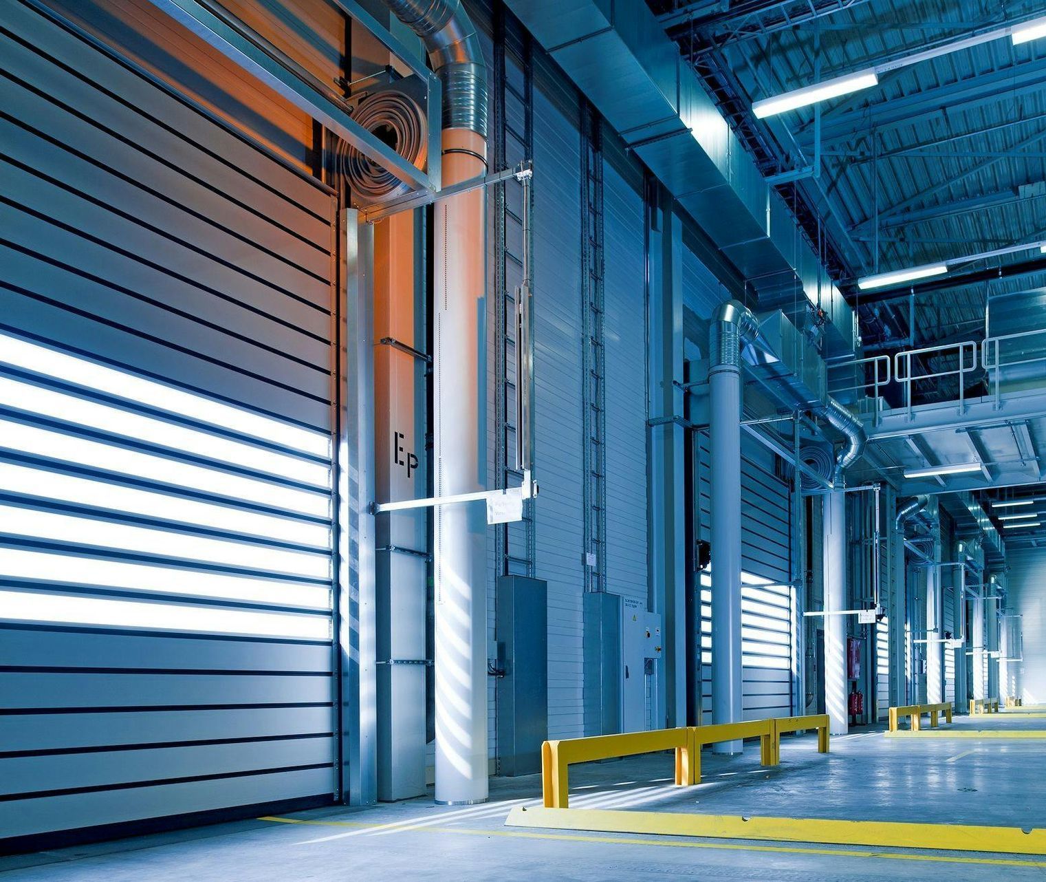 A large warehouse with a lot of doors and a yellow barrier