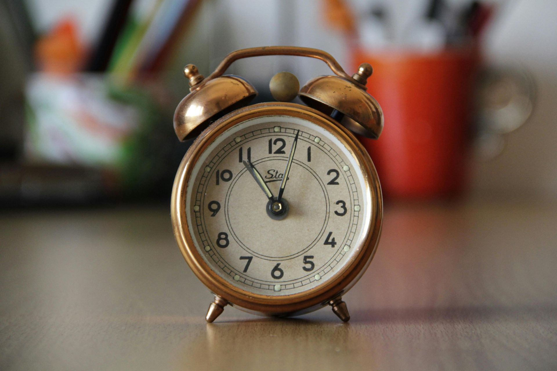 A gold alarm clock is sitting on a wooden table.