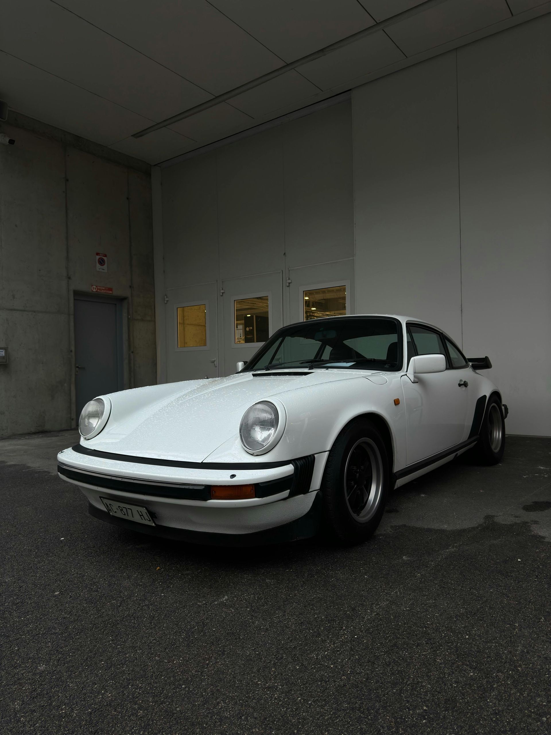 A white porsche is parked in front of a building