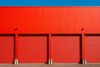 A red building with red garage doors and a blue sky in the background.