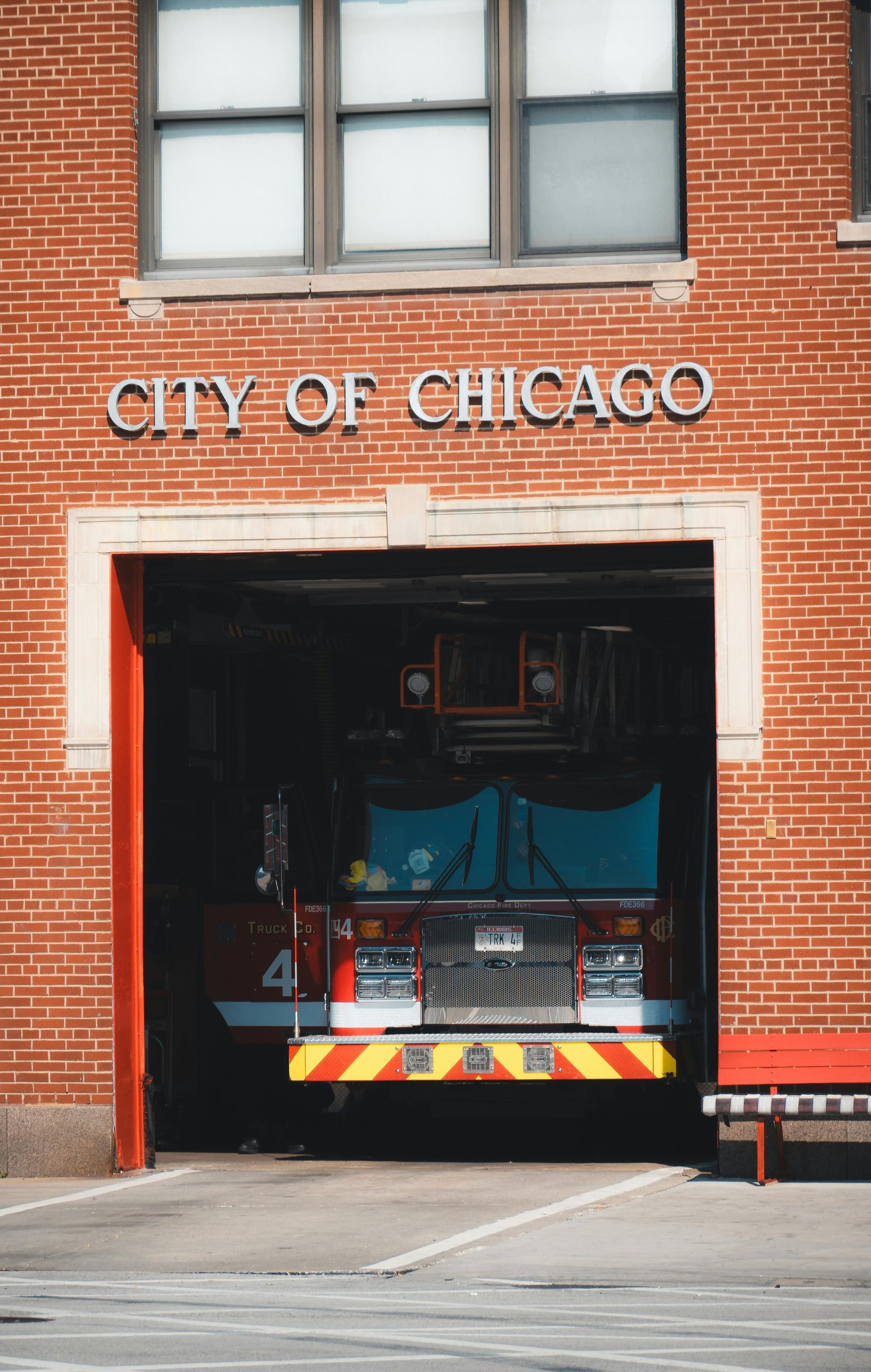A fire truck is parked in the doorway of a city of chicago fire station.