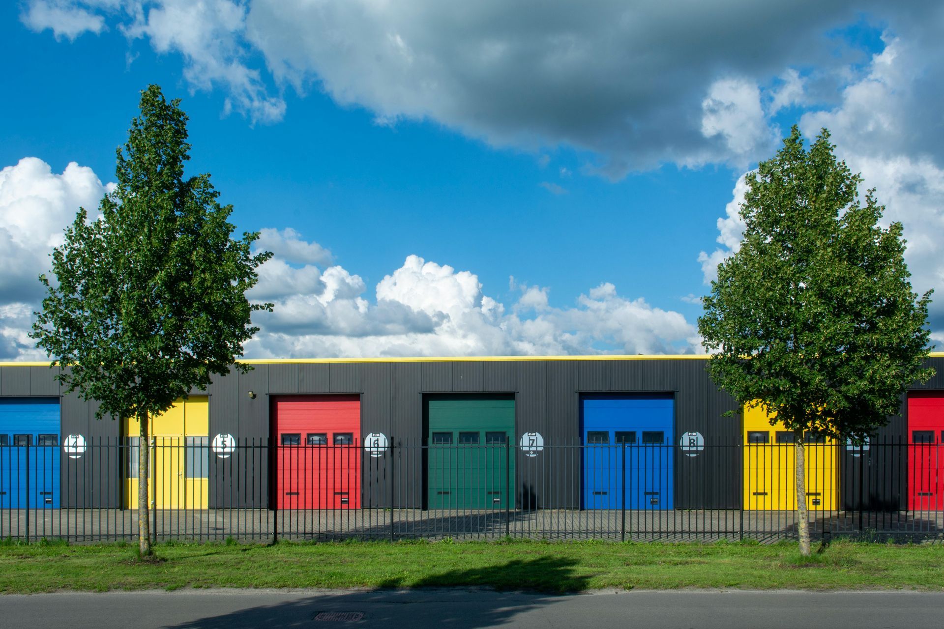A row of colorful garage doors are lined up in front of a building.