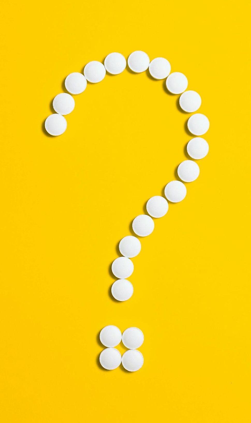 A question mark made of white pills on a yellow background.