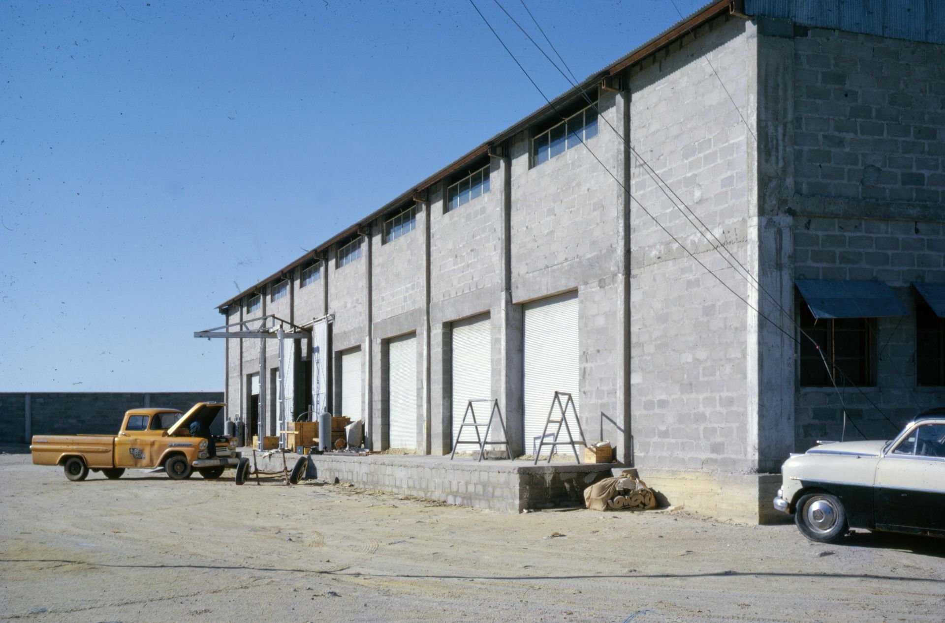 Two yellow trucks are parked in front of a warehouse