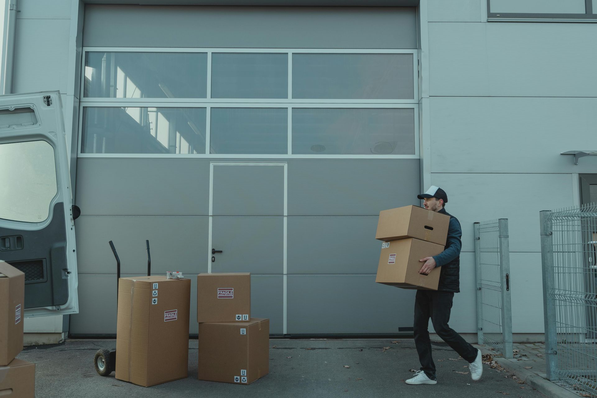 A man is carrying boxes in front of a garage door.