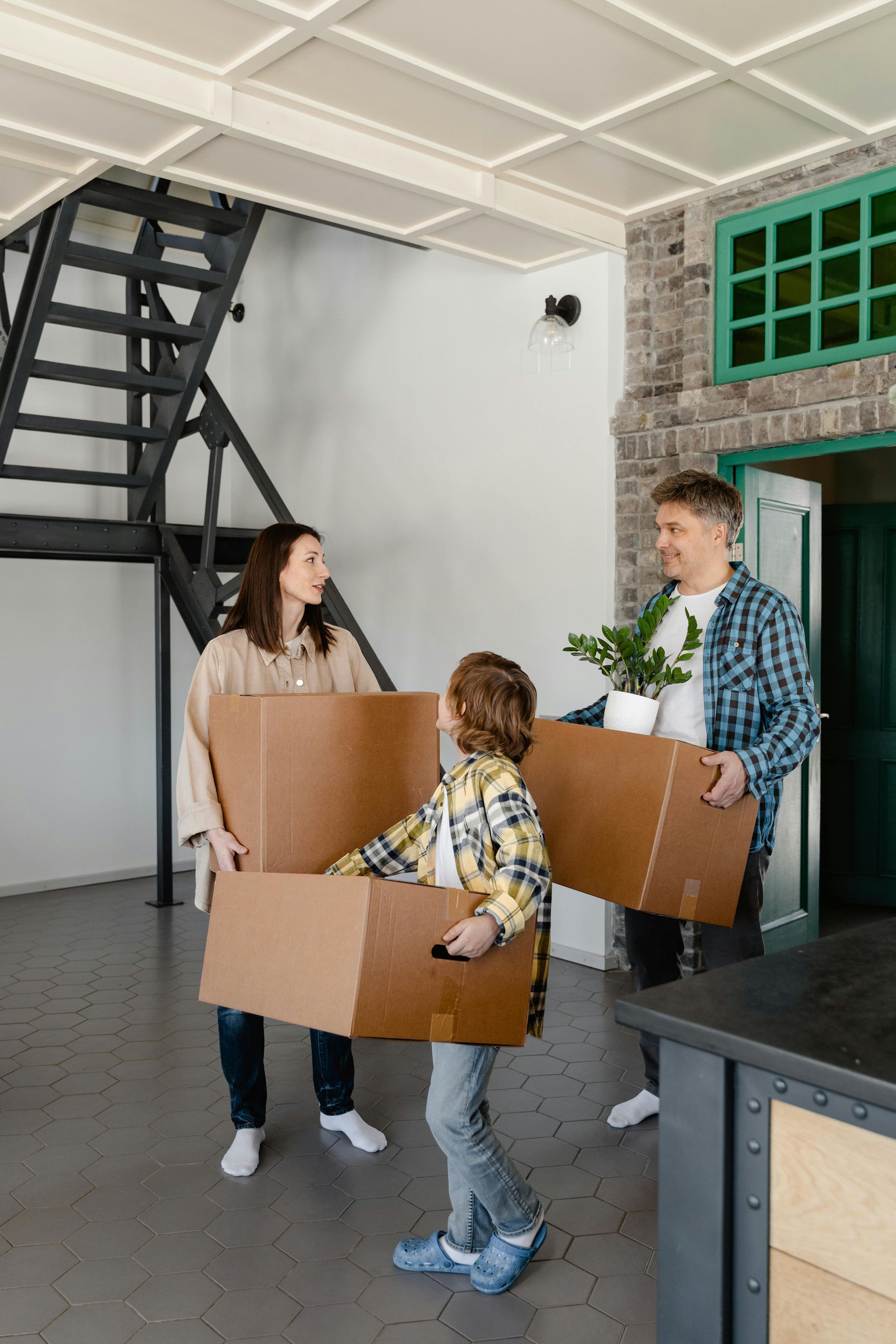 A family is carrying cardboard boxes into a new home.