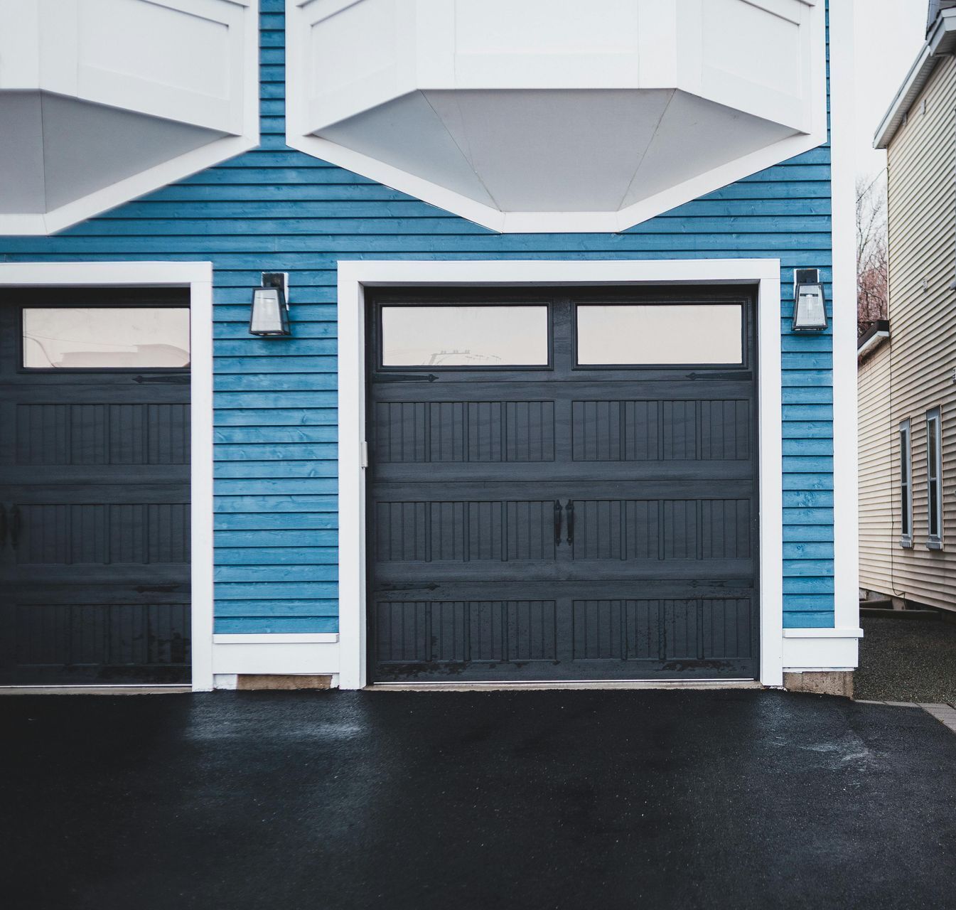 A blue and white house with two black garage doors