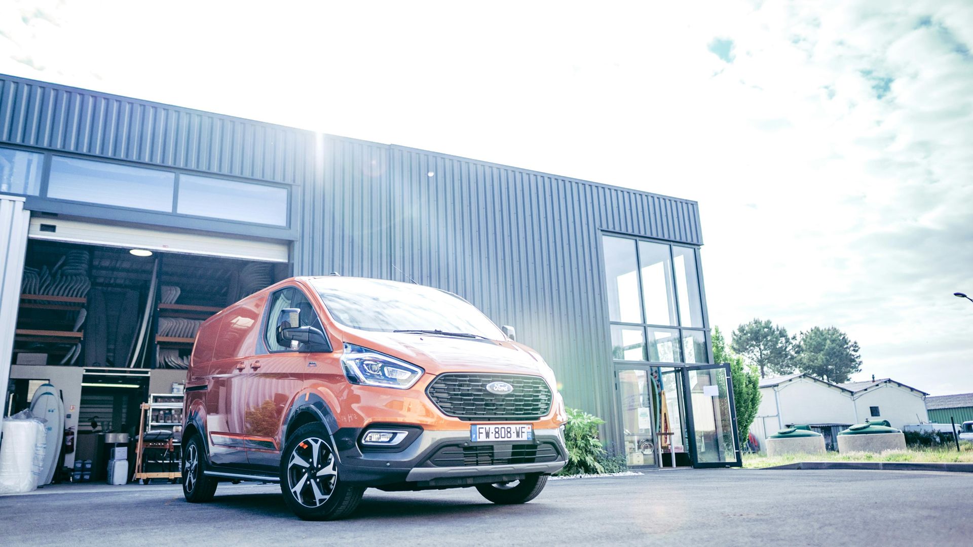 An orange van is parked in front of a building.