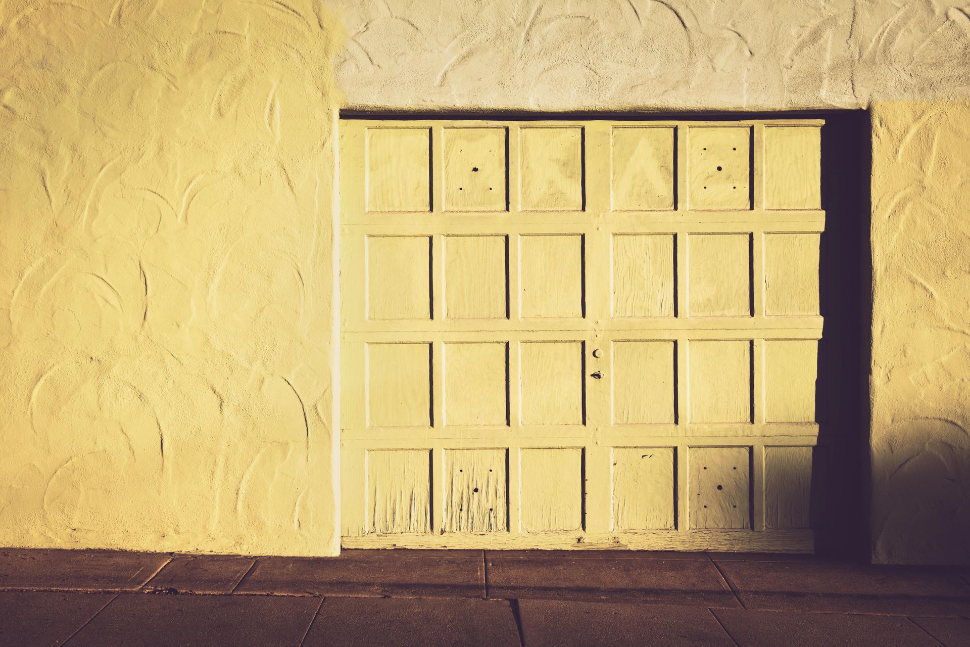 A yellow garage door is sitting on a yellow wall.