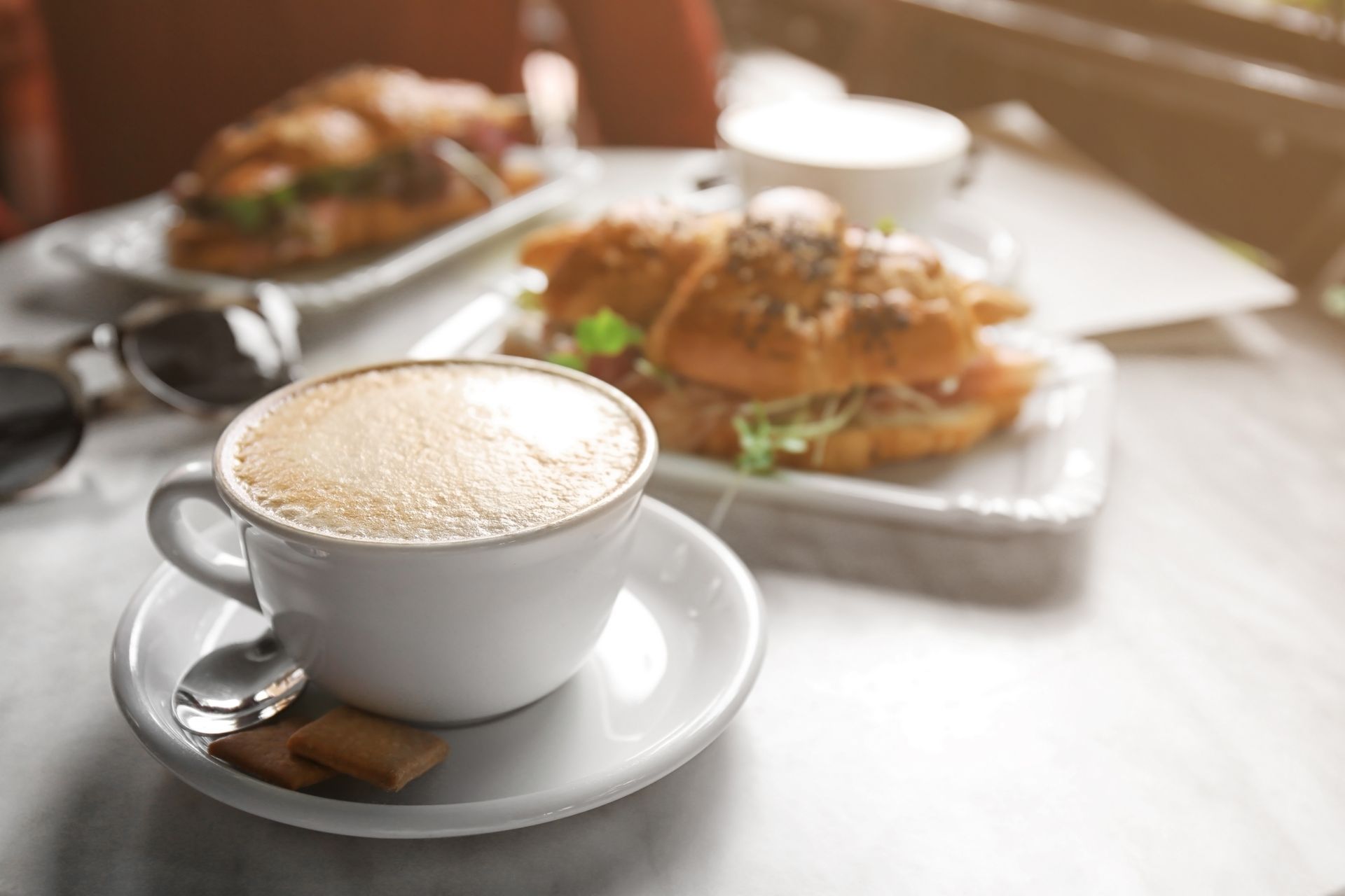 Overhead view of four people sitting at a round table sharing a meal of burgers, fries, and salad in a restaurant.